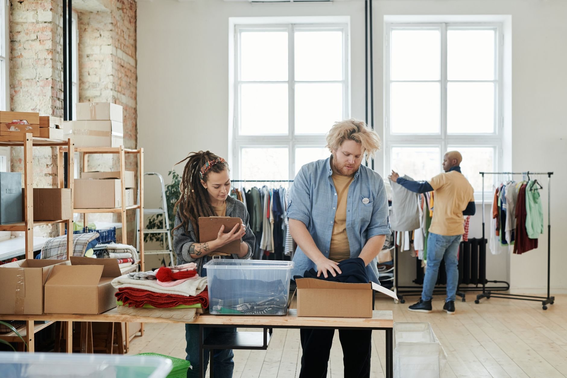 People organizing clothes in a bright, urban clothing store with teamwork and focus.